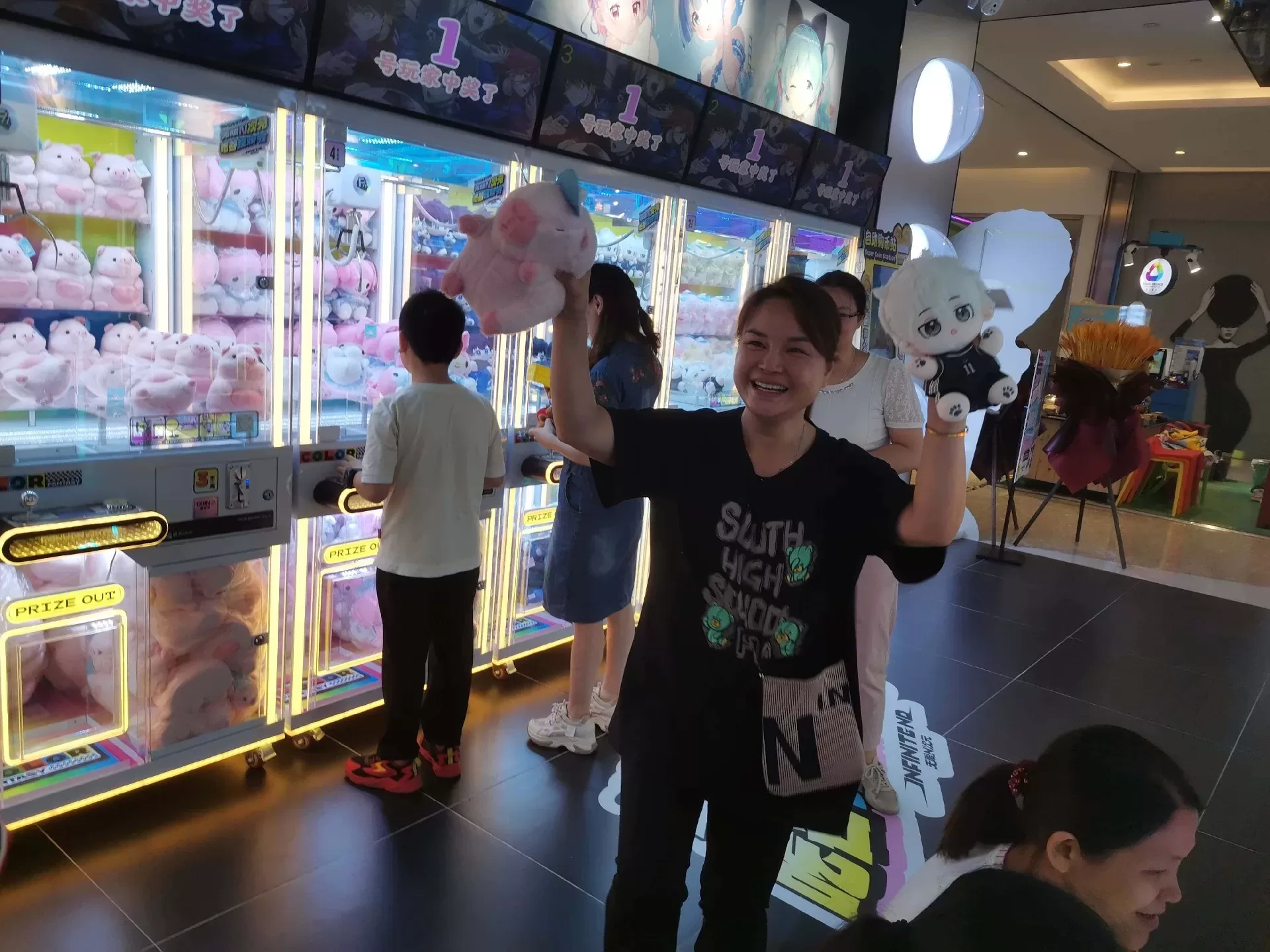 Players enjoying claw machines in shopping mall